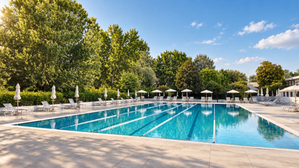 La piscina esterna di Ronchiverdi con lettini e ombrelloni, circondata dal verde